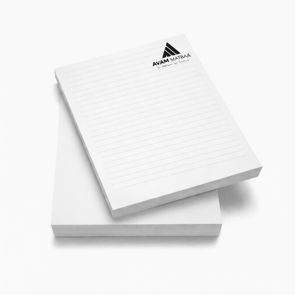 Avam Matbaa logolu çizgili notluk kağıtları, üst üste yerleştirilmiş blok halinde gri arka planda sergileniyor.